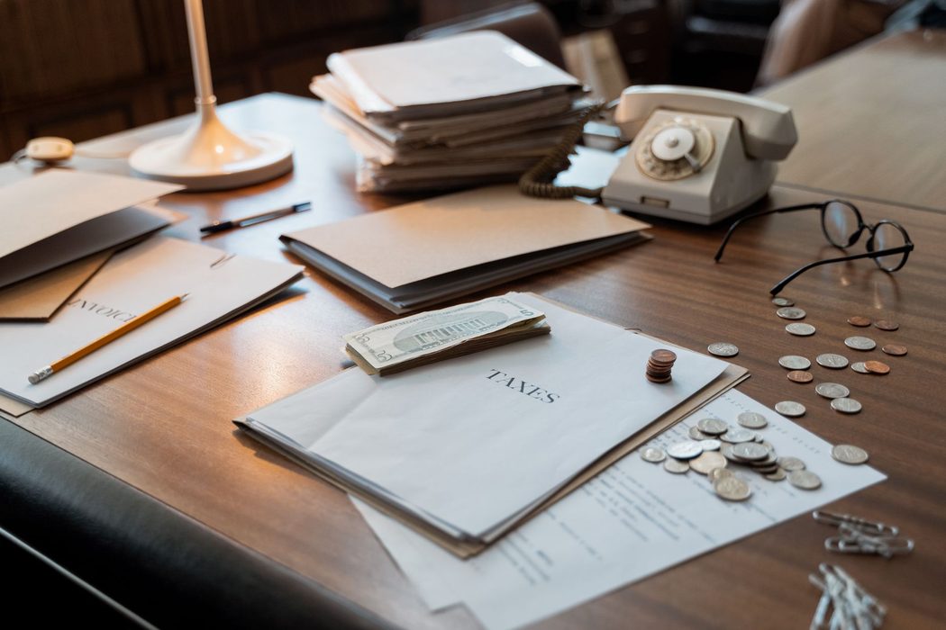 A stack of paper income statements and tax documents on a wooden desk